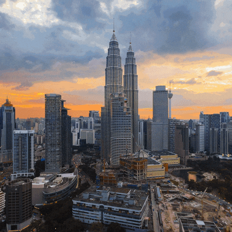Video gif. A time lapse of the Kuala Lumpur skyline going from day to night.