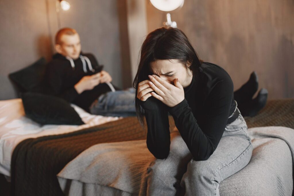 A couple experiencing tension and sadness in a modern bedroom setting.