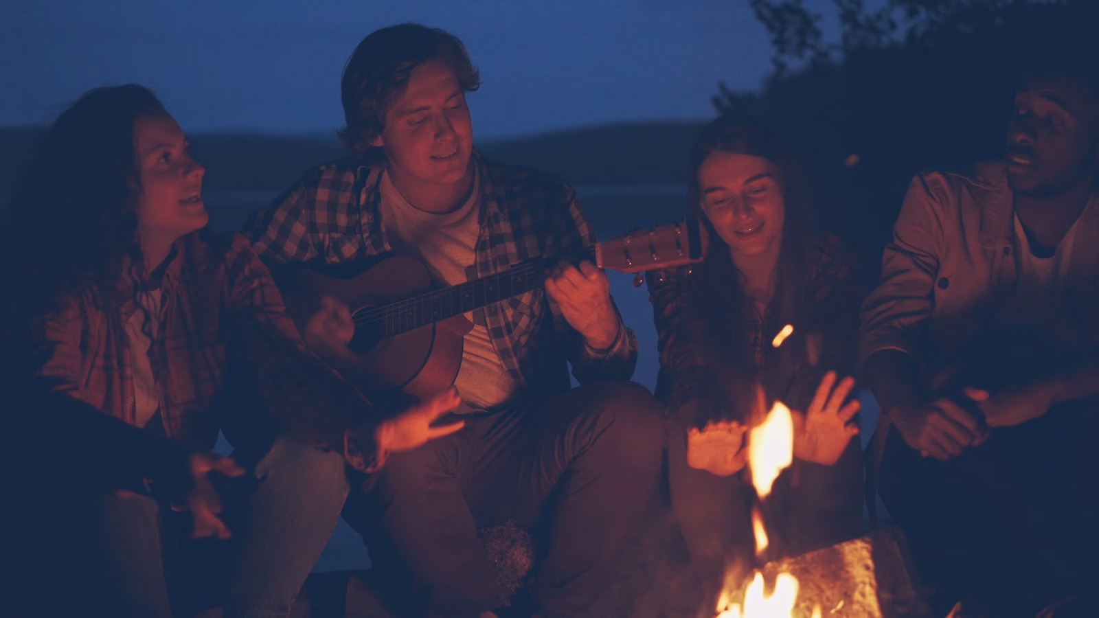 Friends gathered around a campfire at night