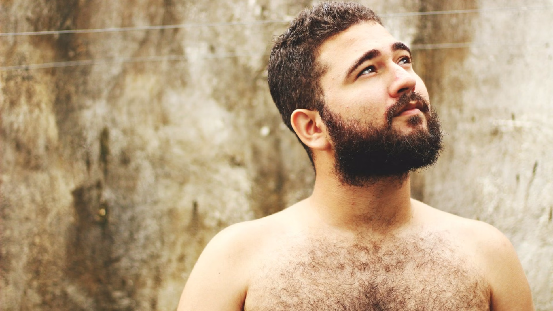 topless man near beige wall